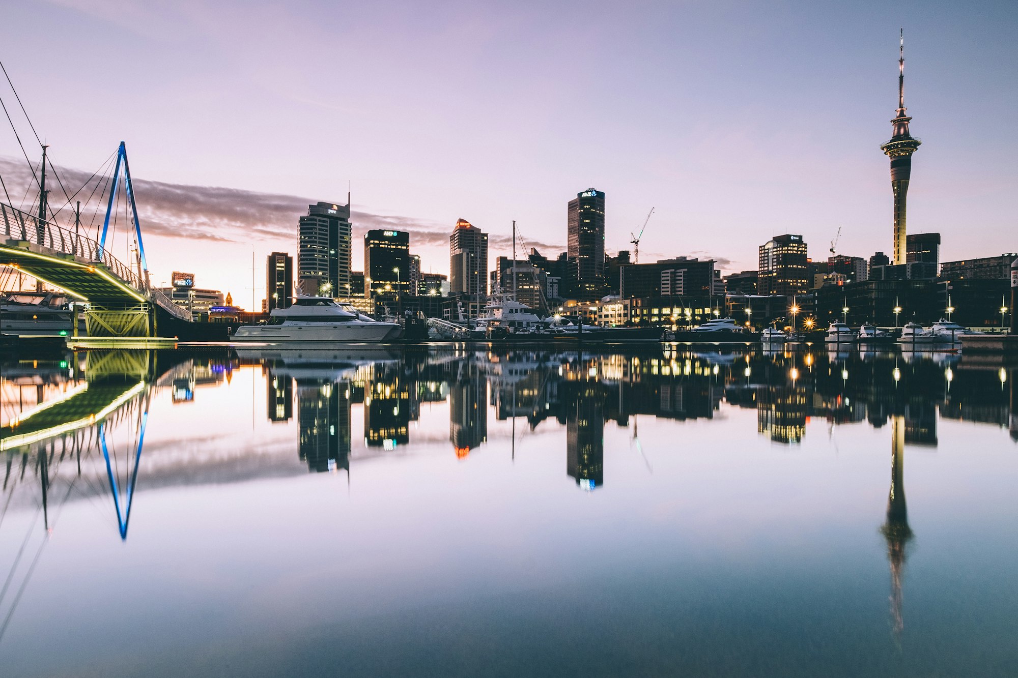 Auckland waterfront skyline with the Sky Tower reflected in the harbour at dusk